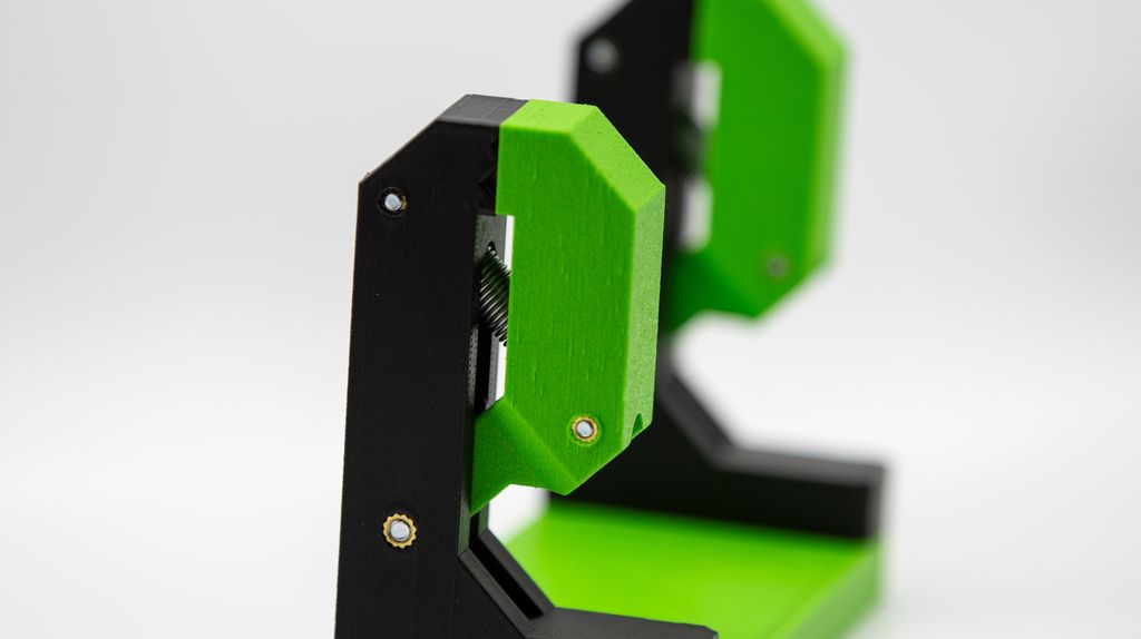 Grønt og svart stativ med en klemme øverst. Foto.