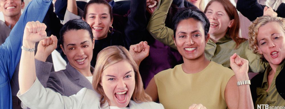 En gruppe inspirerte og glade mennesker jubler med hendene i lufta. Foto.