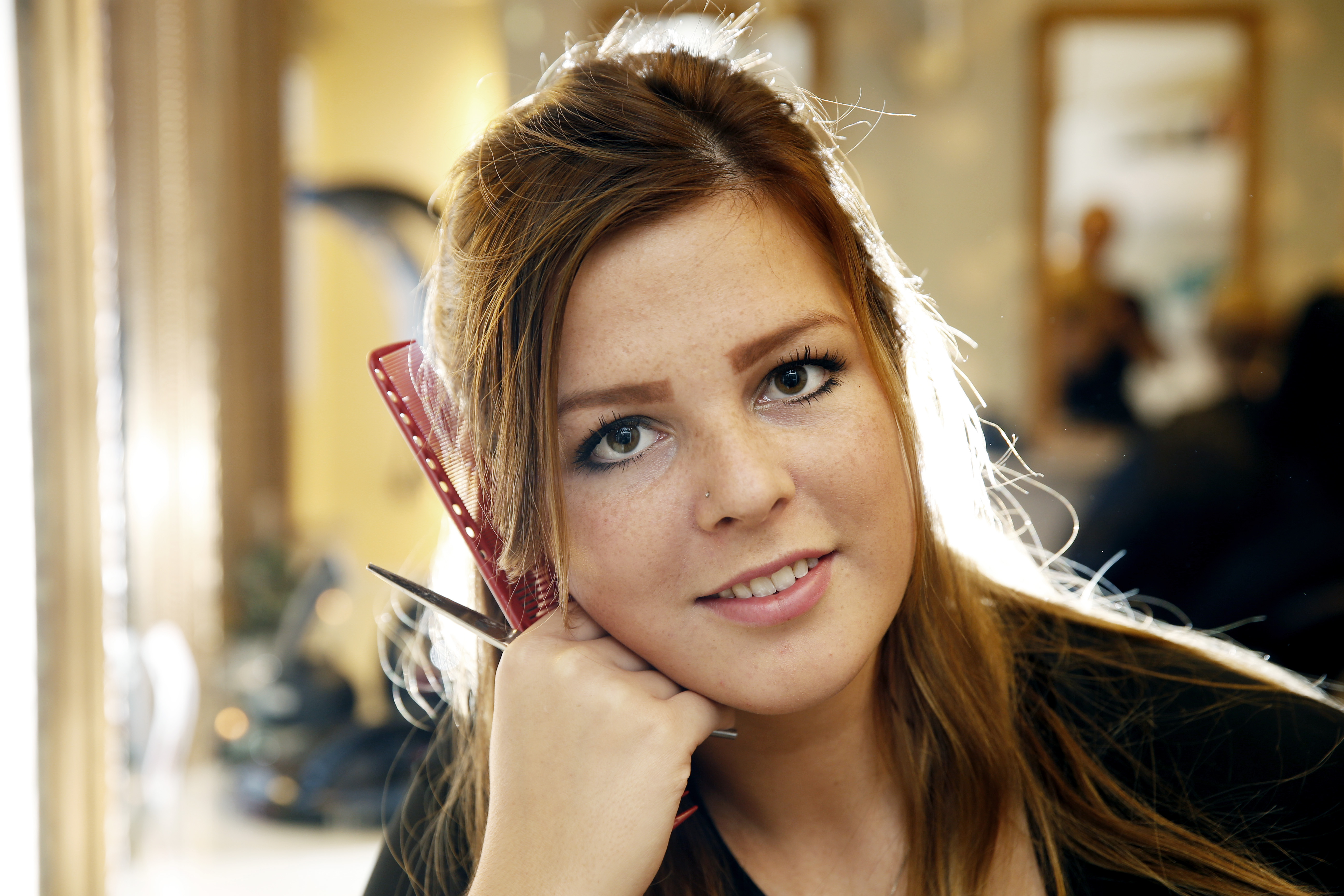 Ung kvinne som holder kam og saks. Foto.