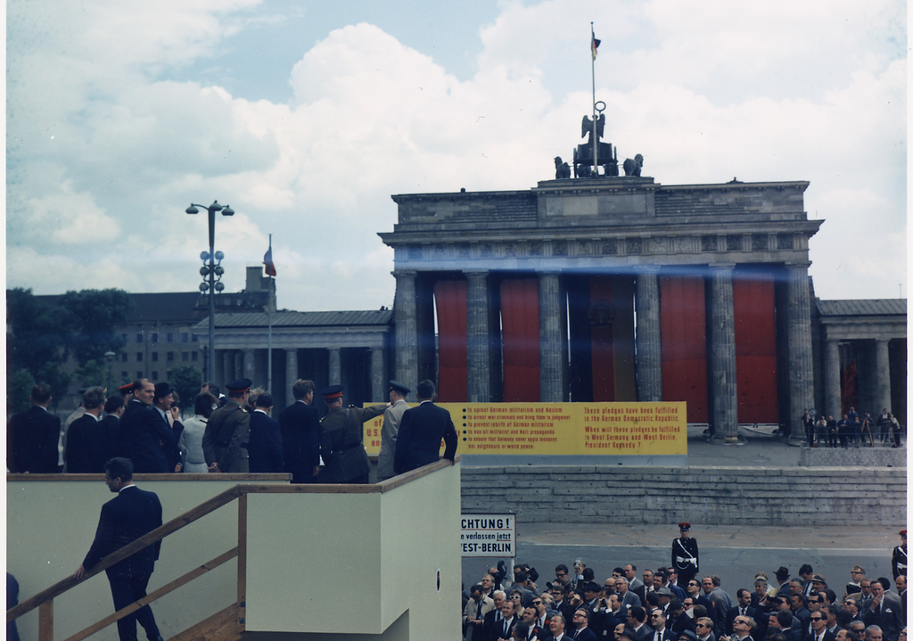 President's Trip to Europe- President on platform overlooking Brandenburg Gate. President Kennedy, others in party, spectators. West Berlin, Germany. Photo.