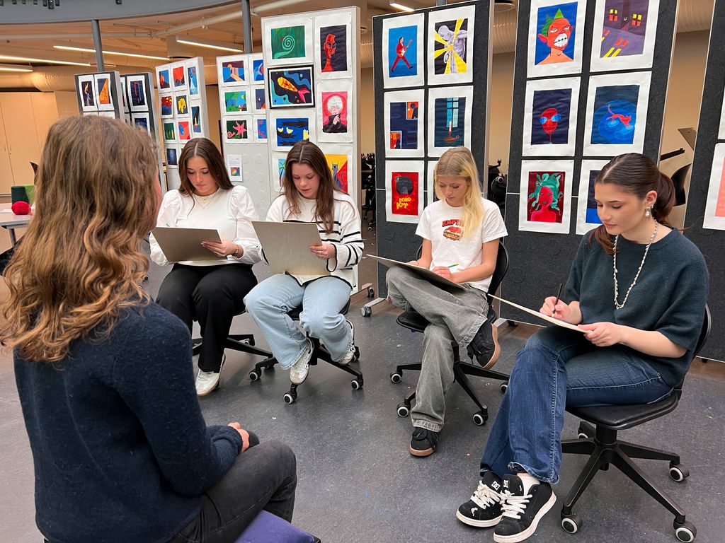 Ein elev sit som modell framfor fire medelevar som teiknar henne. Foto.