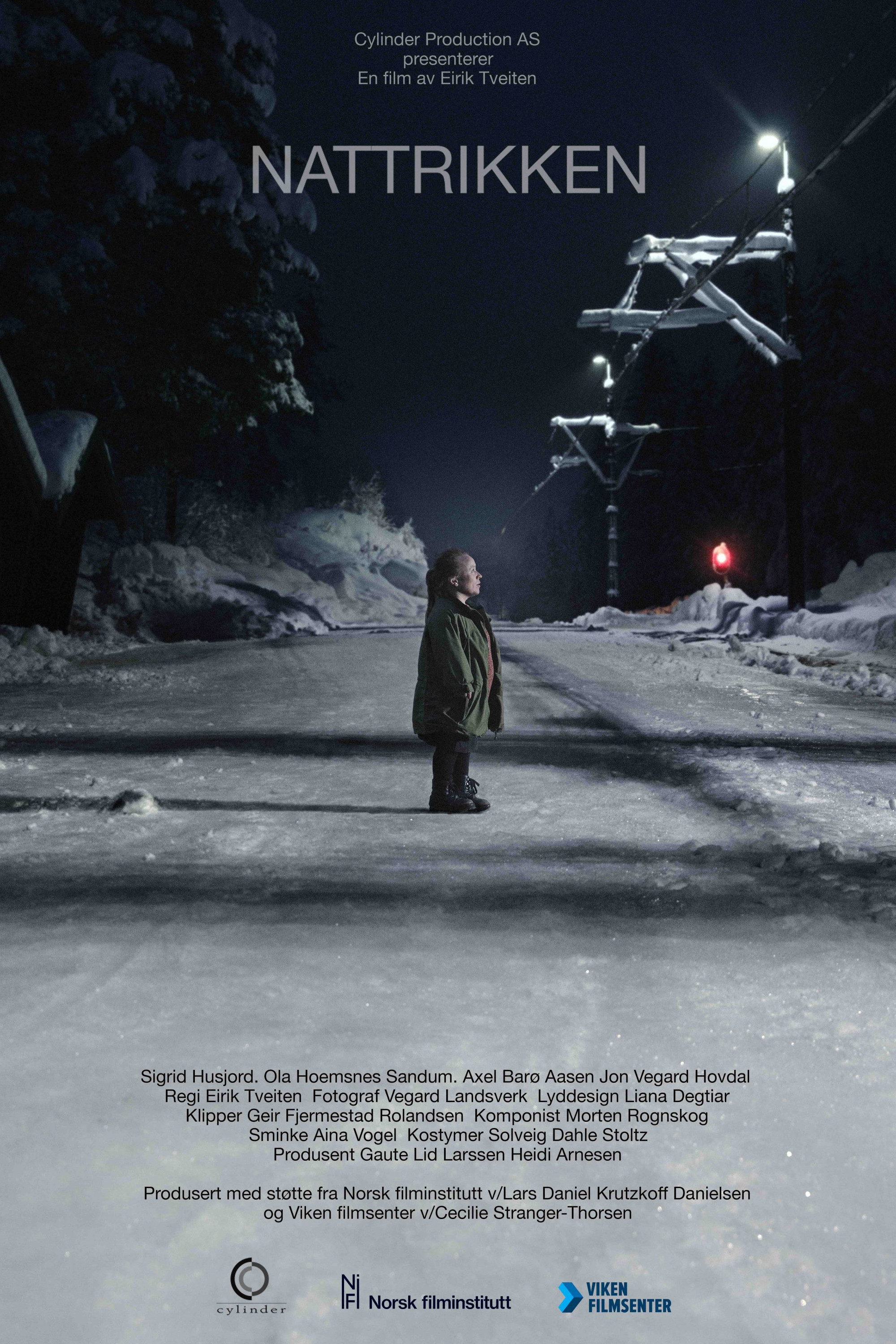 Filmplakat for kortfilmen Nattrikken. Biletet viser ei kortvaksen kvinne som ein sein kveld står ved eit trikkespor i eit snødekt landskap. Filmplakat.