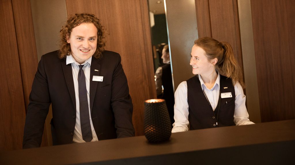 Kvinnelig og mannlig resepsjonist ved hotellresepsjonen. Foto.
