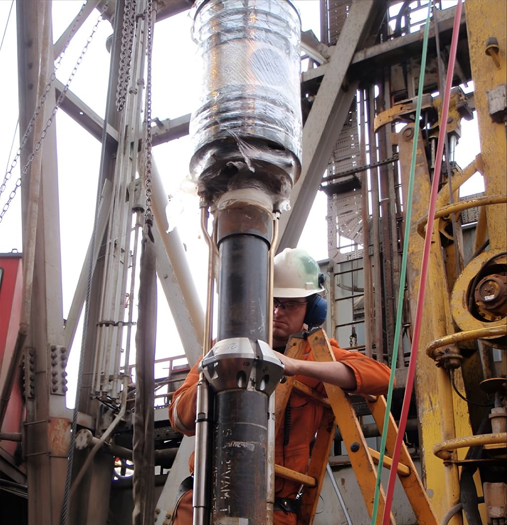 En oljearbeider i oransje arbeidsklær klargjør en tubing hanger for installasjon. Foto.