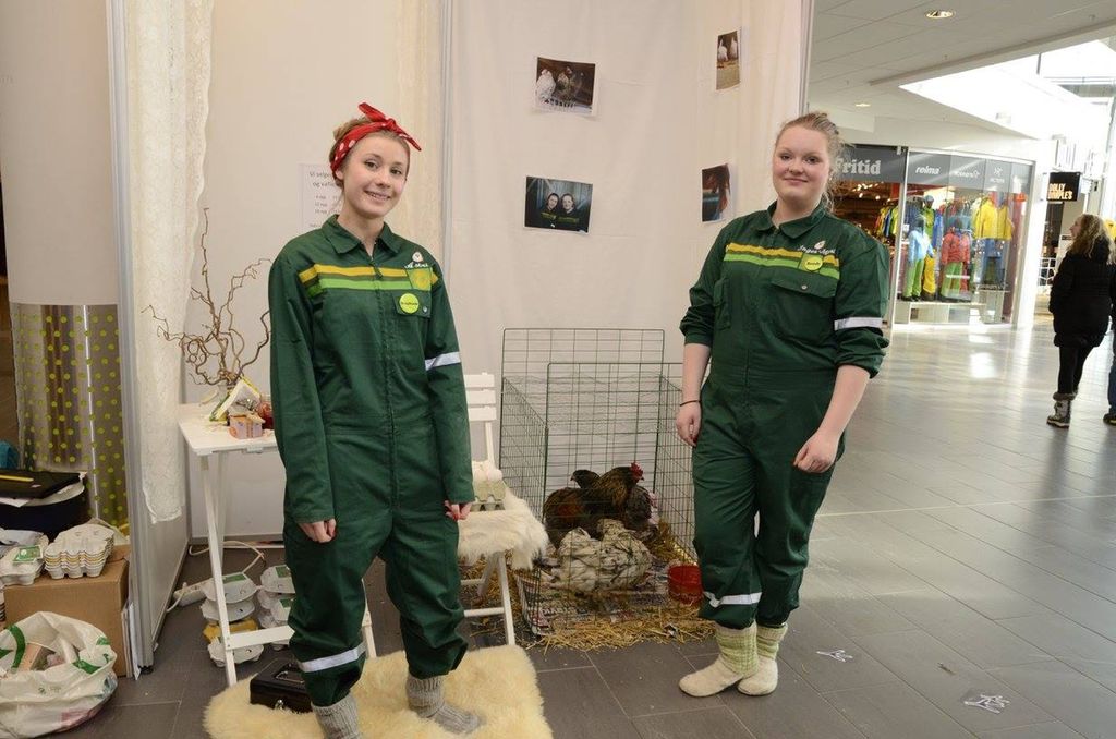 To jenter med Felleskjøpet-overaller står på stand med høner og egg. Foto.