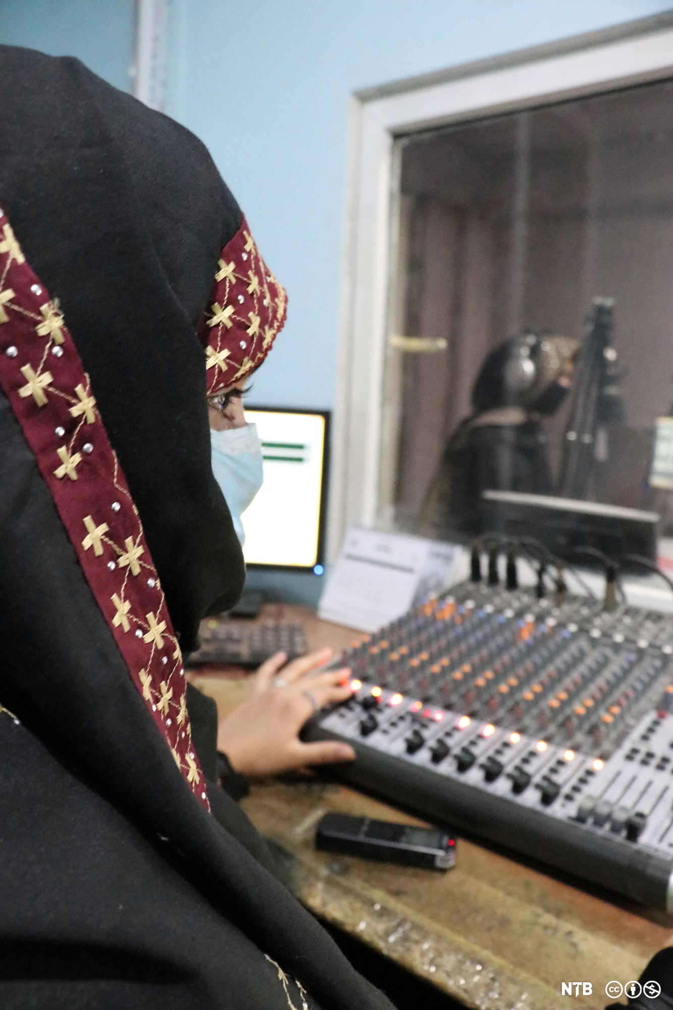 Kvinnelig radiojournalist med nikab produserer radiosending. Foto.