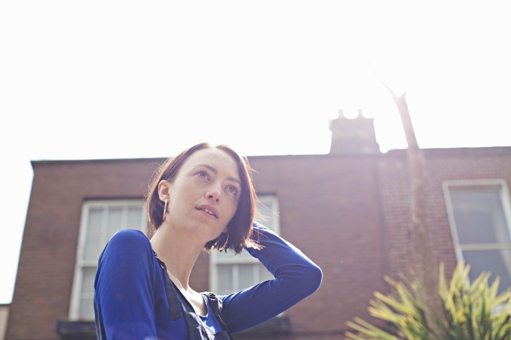 Ung jente ser seg bakover skulderen med et flørtende blikk. Foto.