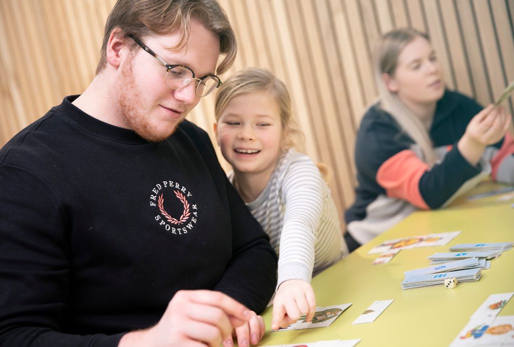 Vaksen mann med svart genser og briller speler Mix Max med ei jente.  Foto.