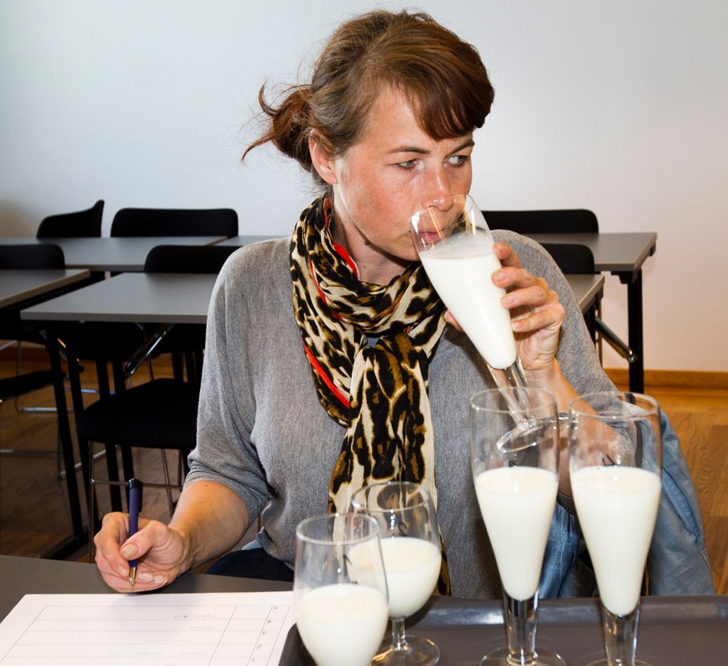 En dame smaker på flere typer melk. Hun har et skjema foran seg. Foto.