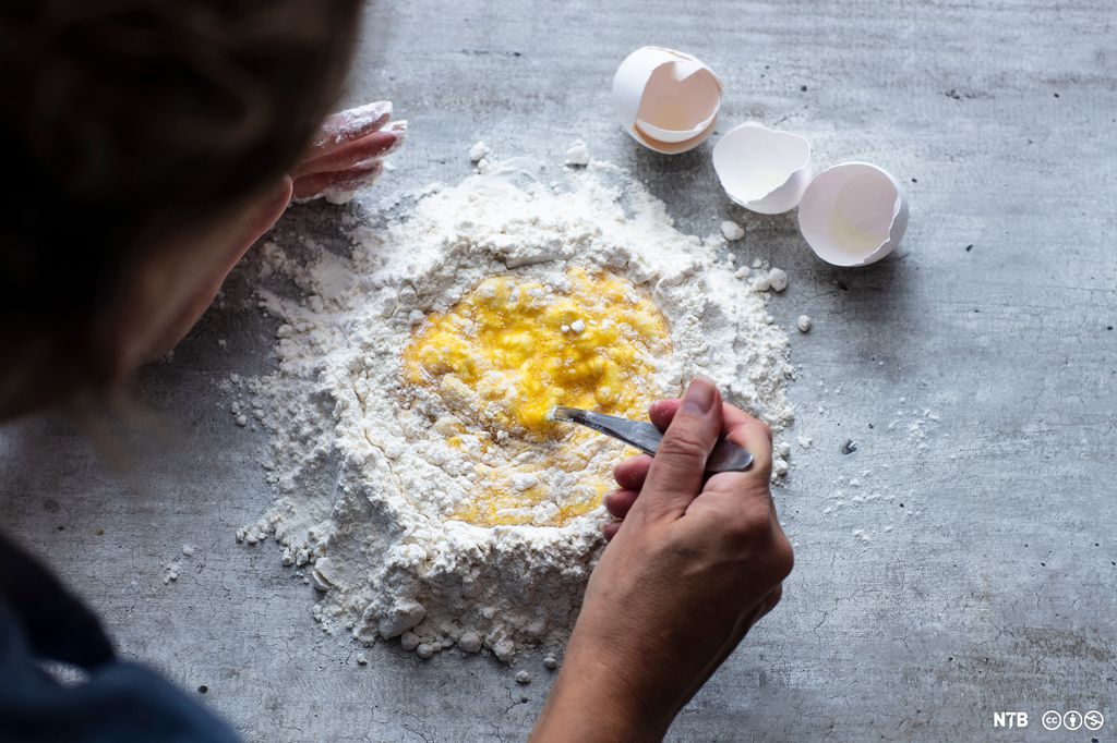 En person rører med gaffel i en melgrop med egg i midten. Foto.