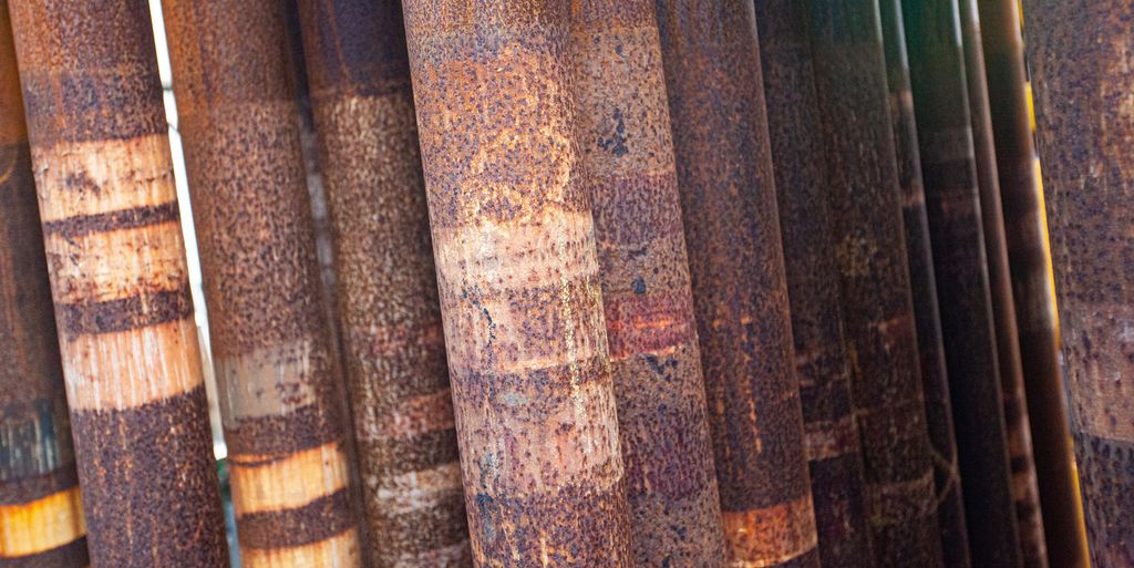 Rustne borerør står stablet sammen oppreist. Foto.