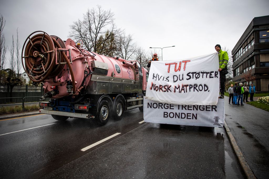 To personer langs veien holder opp plakater med teksten Tut hvis du støtter norsk matprod. og Norge trenger bonden til trafikken som kjører forbi. Foto.