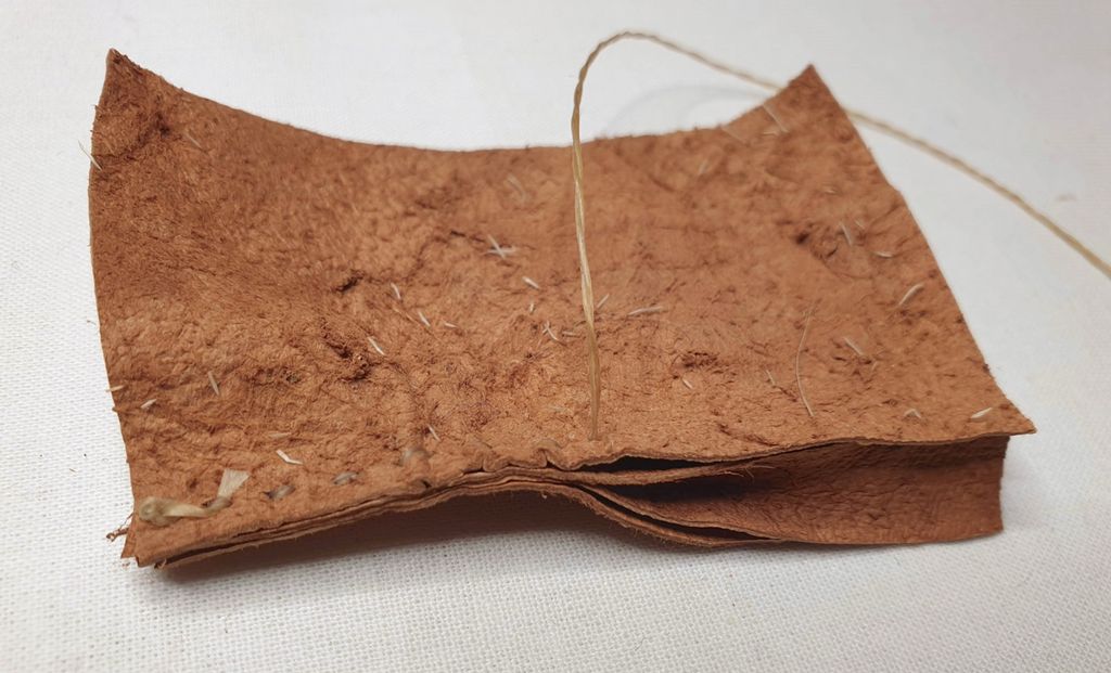 Fotografi av at to deler skinn blir sydd sammen med et mellomlegg som er brettet dobbelt.