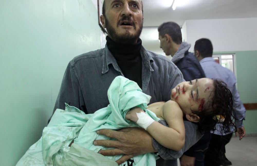 Ein mann ber eit såra barn i ein korridor. Foto.