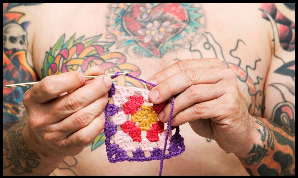 Tatovert mann som hekler. Foto.