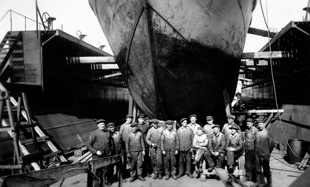 Arbeidere foran et stort skip på hvalfangststasjonen Grytviken, Sør-Georgia. Foto.
