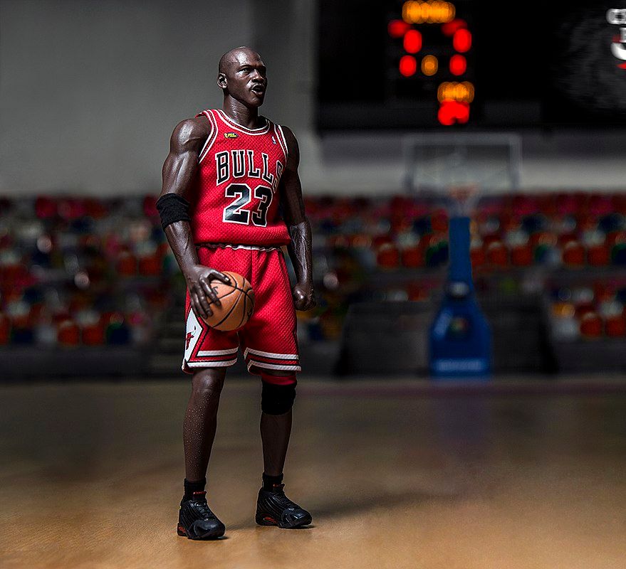 En stor, kraftig mann med rød Chicago Bulls-drakt og basketball i hånden står på en bane. Foto.