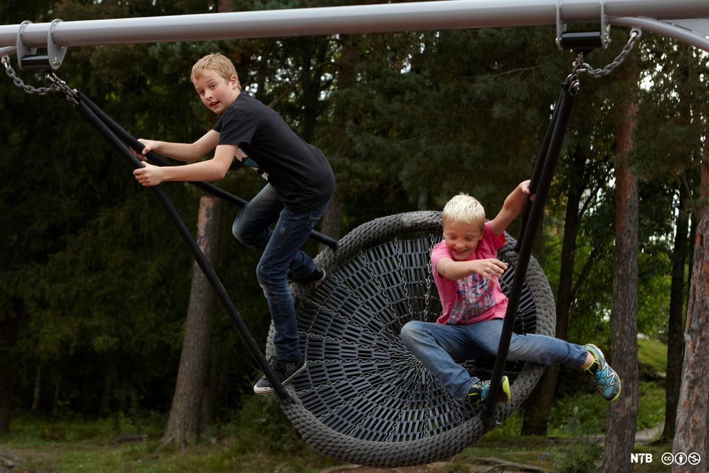 To gutter på ei stor fugleredehuske. Den ene står og holder i tauet og gir fart, den andre sitter. Foto. 