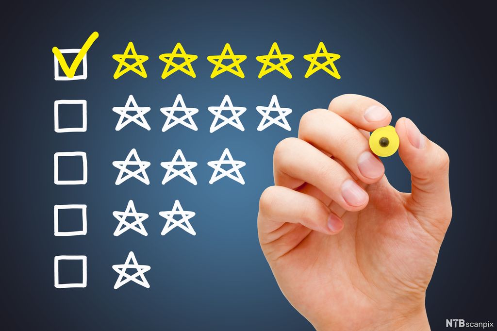 Hånd som haker av for fem av fem stjerner på kundetilfredshet. Foto.