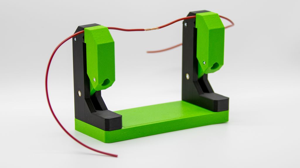 Grønt og svart stativ med to tårn som holder to ledninger sammen. Foto.