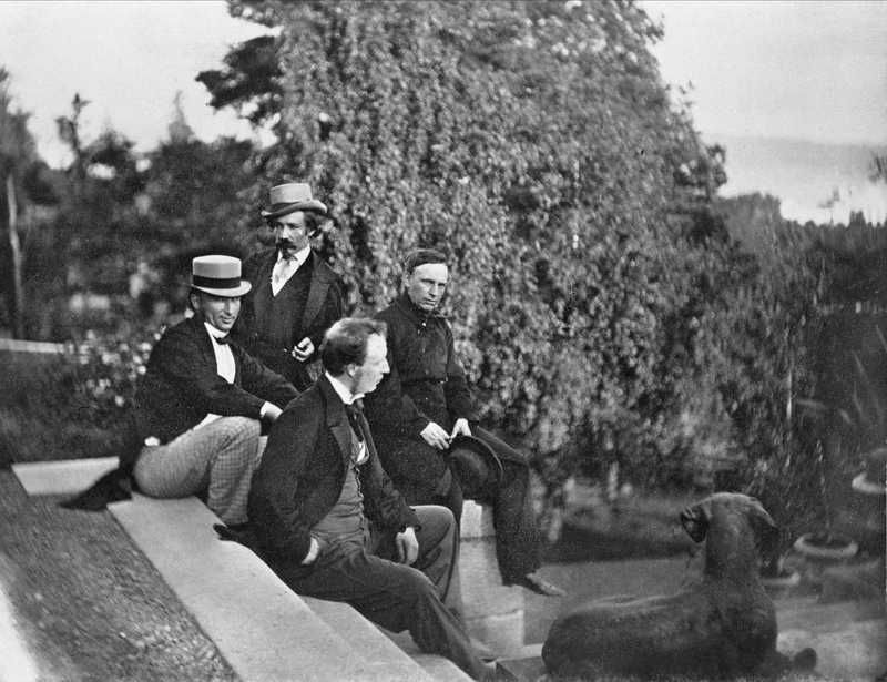 Johan Welhaven sitter på ei trapp med tre andre menn. Foto.