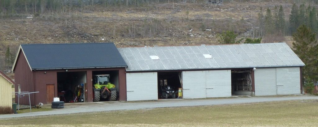 Stor garasje med plass til blant annet en traktor og andre store maskiner. Foto.
