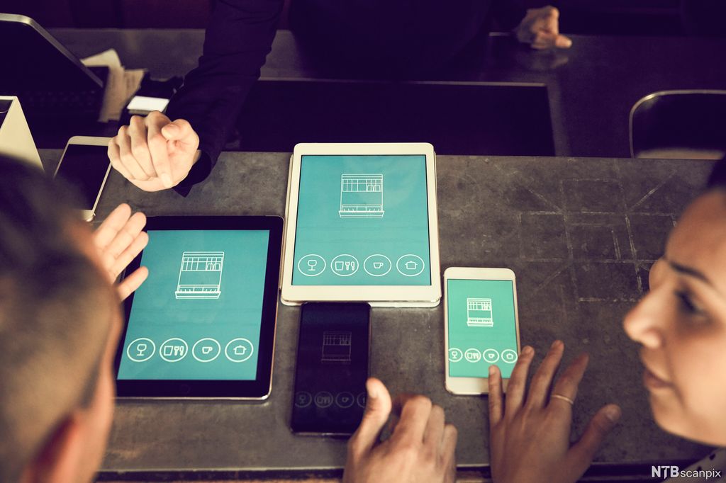 Mann og kvinne med ulike skjermer med app. Foto.