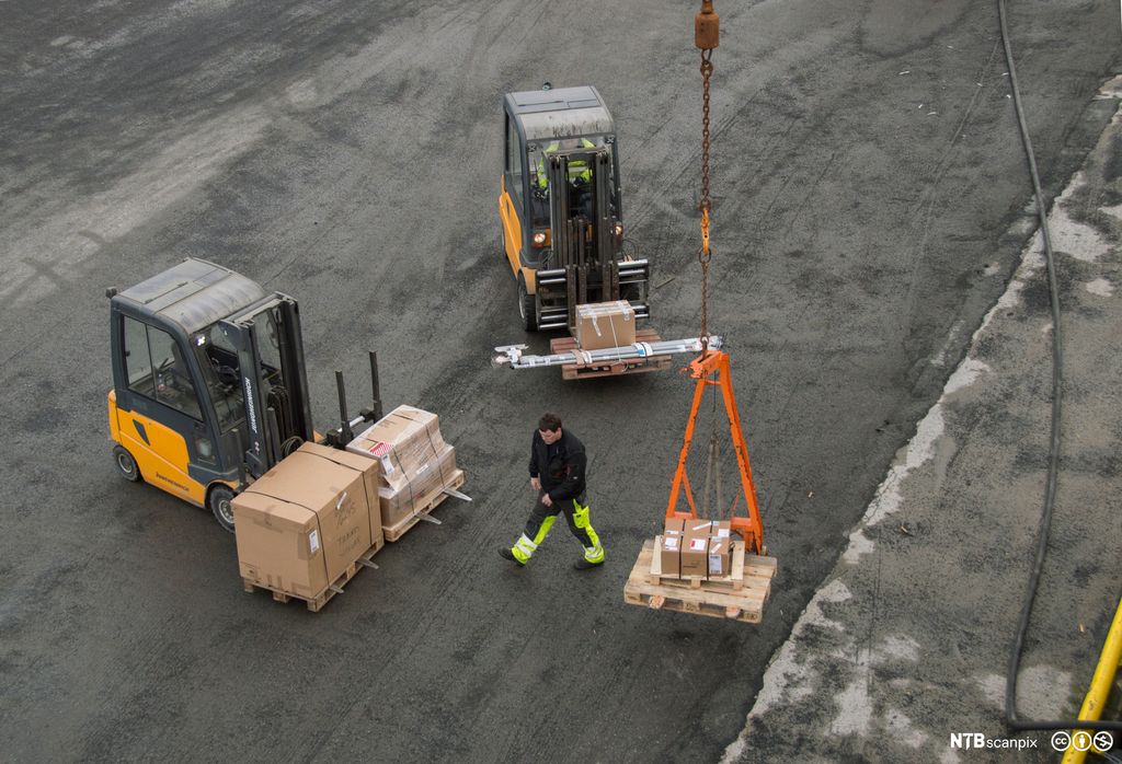 To gaffeltrucker og en mann på kai der varer heises . foto.