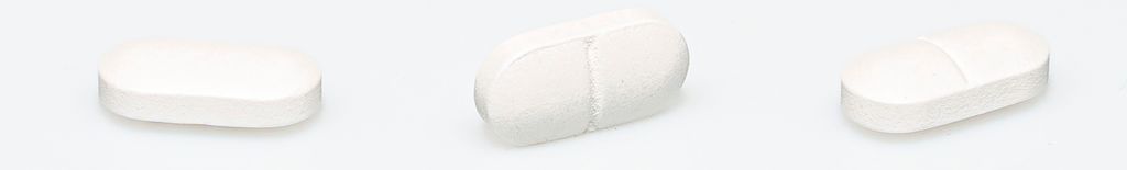 Tre avlange, hvite tabletter med delestrek. Foto.