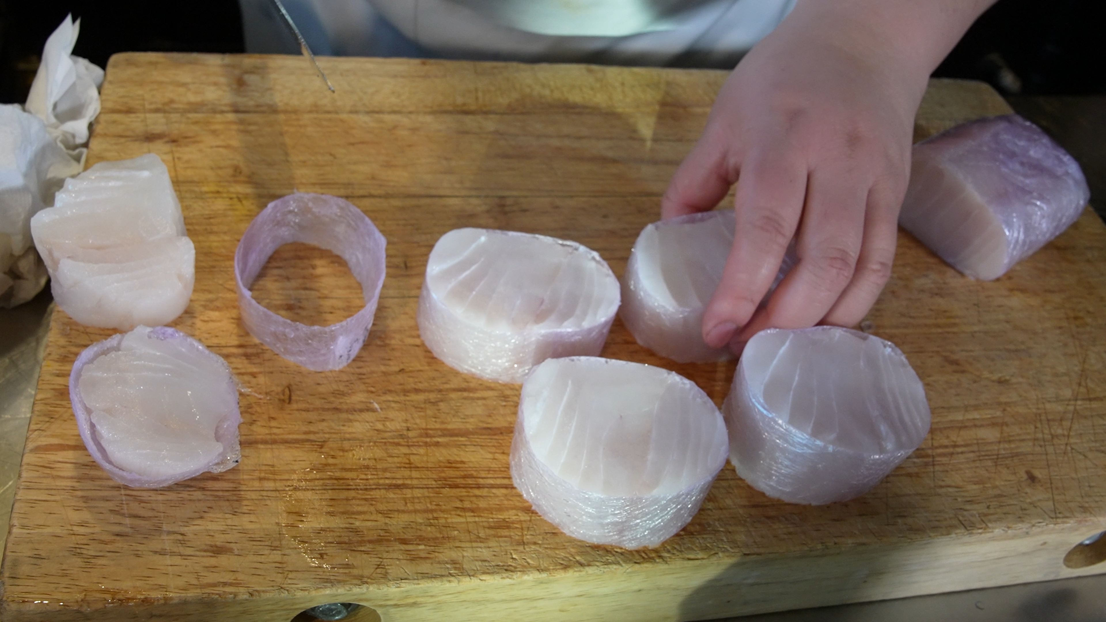 Skreifilet som er rullet stramt i plast til ei pølse, kuttes opp i serveringsstykker. Foto.