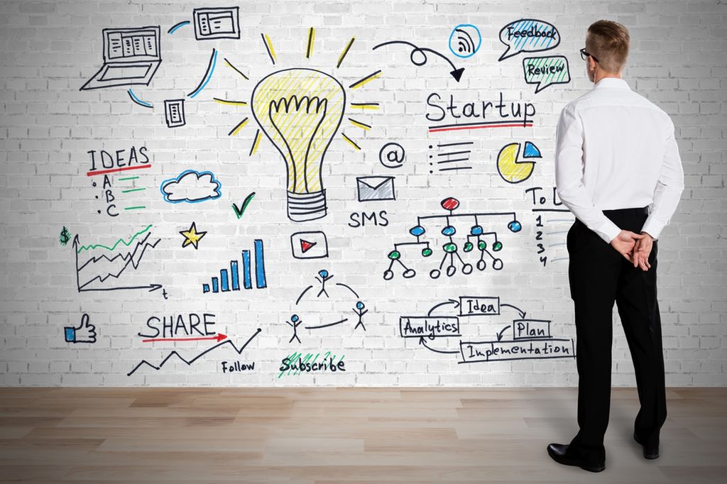 Forretningsmann ser på planleggingen av virksomheten sin tegnet som en graf på murvegg. Foto.