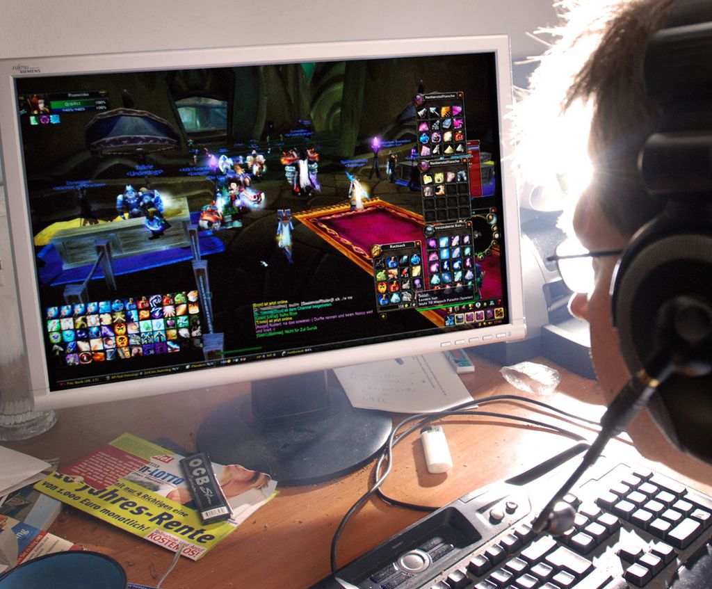 Ein ungdom sit framfor ein pc og speler dataspel. Foto.