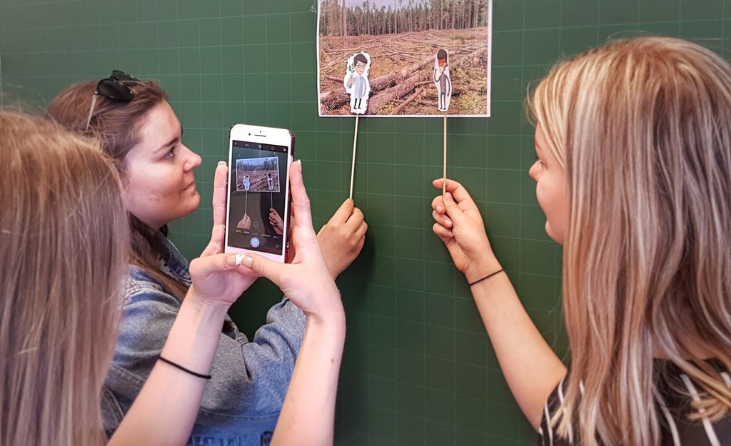 Elever filmer pinnedukker med mobiltelefon. Foto.