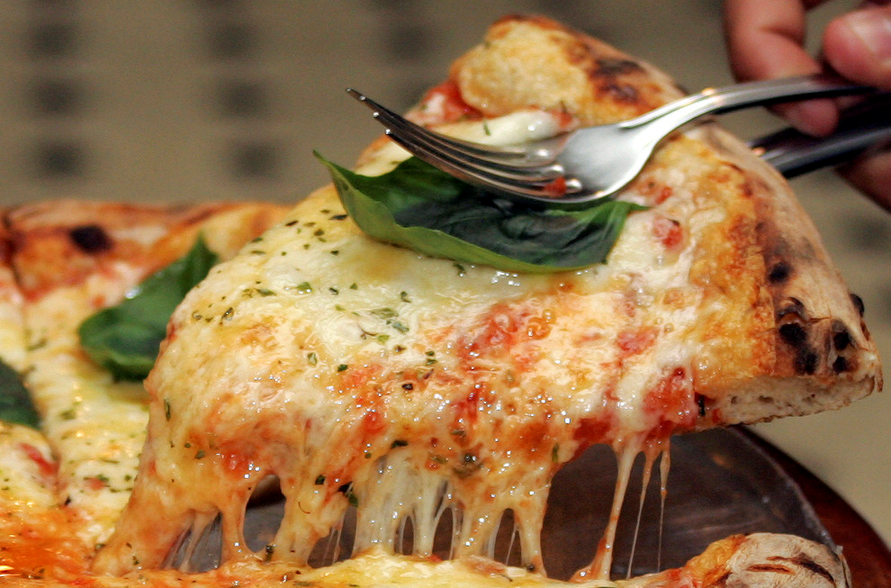 Pizzabit med mengder av smelta ost. Foto