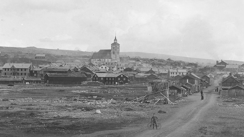 Gate, kirke og hus i Røros. Vi ser noen mennesker i bildet. Foto.