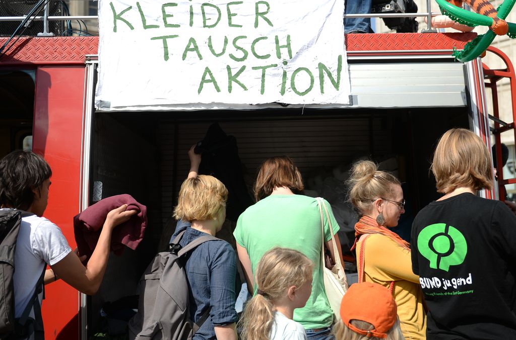 Menneske strøymer til ein marknad der ein kan byte brukte klede med kvarandre. Foto.