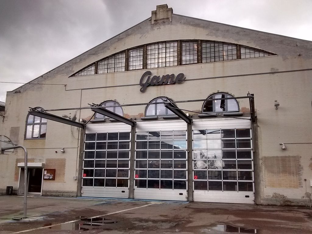 Fasaden til Game Streetmekka, som ligg i ein gammal industrihall. På veggen, over tre store køyreportar, står logoen til Game. Foto.