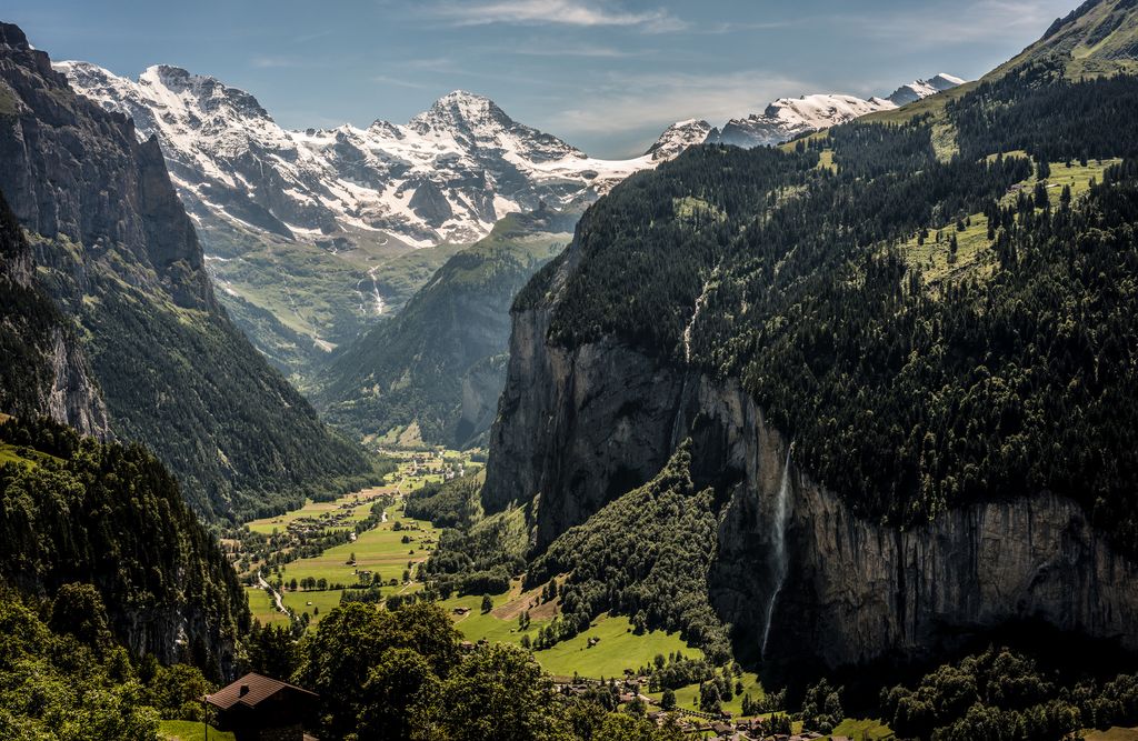 Grønt landskap i Berner Oberland, Sveits, med snødekte fjell i bakgrunnen. Foto.