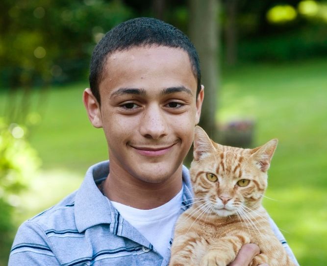 Gutt held ei katt. Foto.