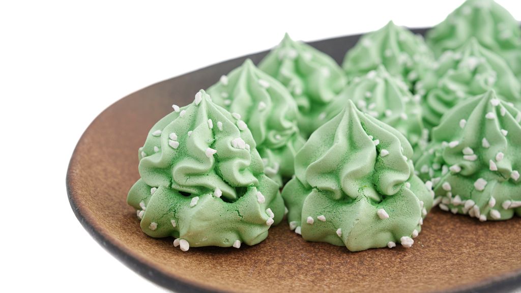 Grøn marengs er sprøytt som små juletre og pynta med kvitt perlesukker. Foto.