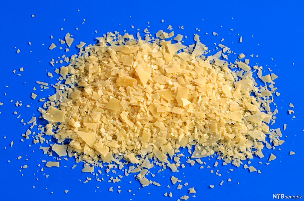 Voks i små flak på blå bakgrunn. Foto.