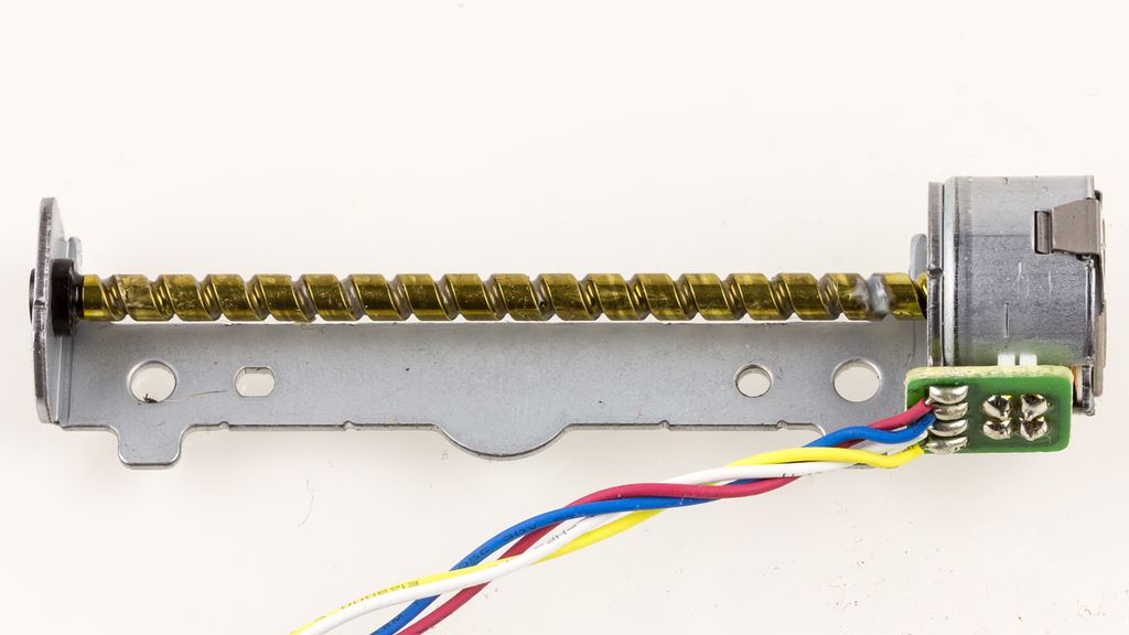 En trinnmotor montert på høyre side av en kuleskrue. Motoren har fire tilkoplingsledninger. Foto.