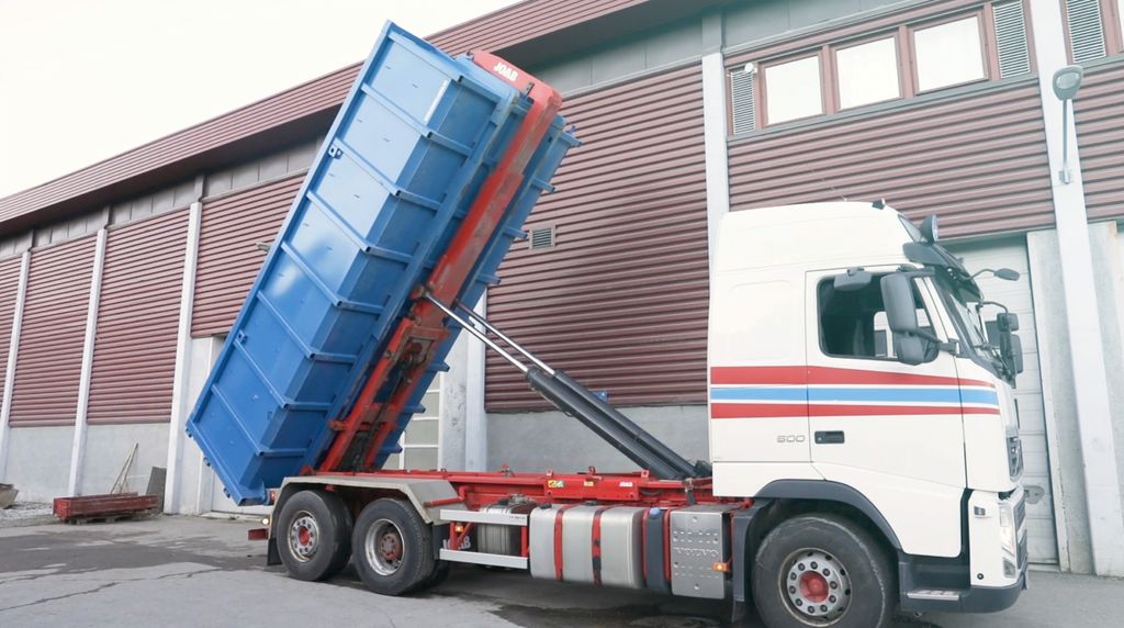 Bildet viser en krokbil som tipper en konteiner med tippfunksjonen.