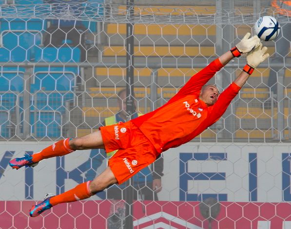 Fotballmålvakt som kaster seg etter ballen. Foto.