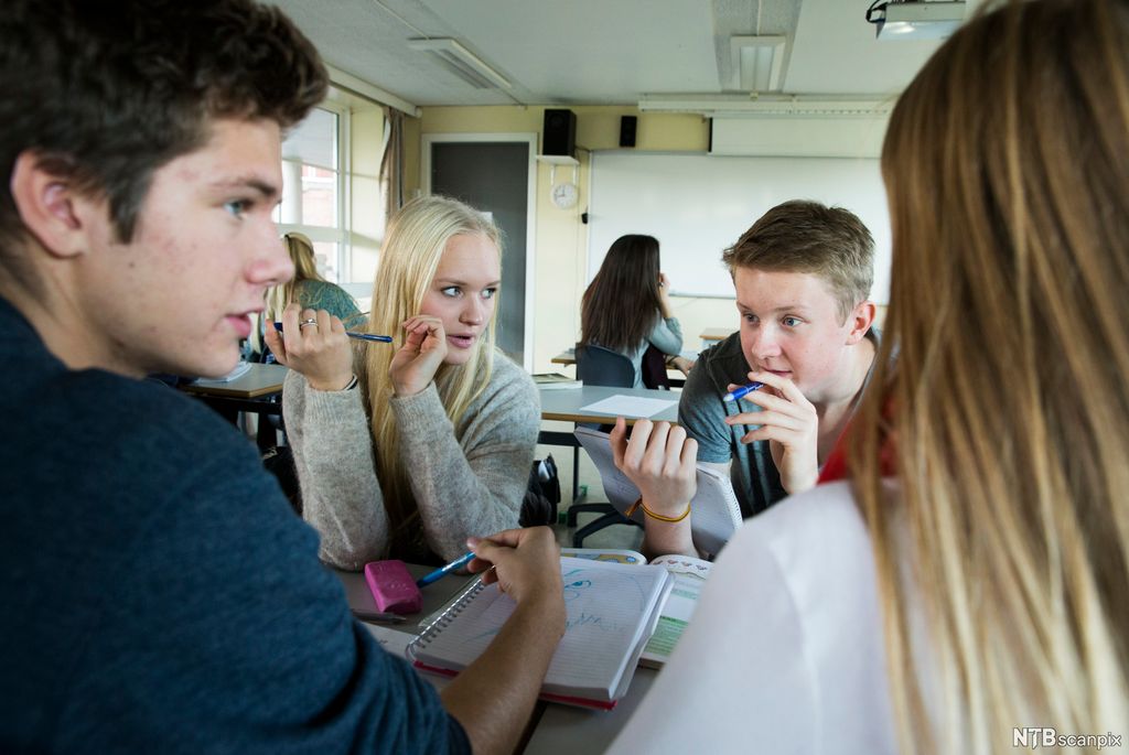 Elever i et klasserom snakker sammen i en liten gruppe. Foto. 