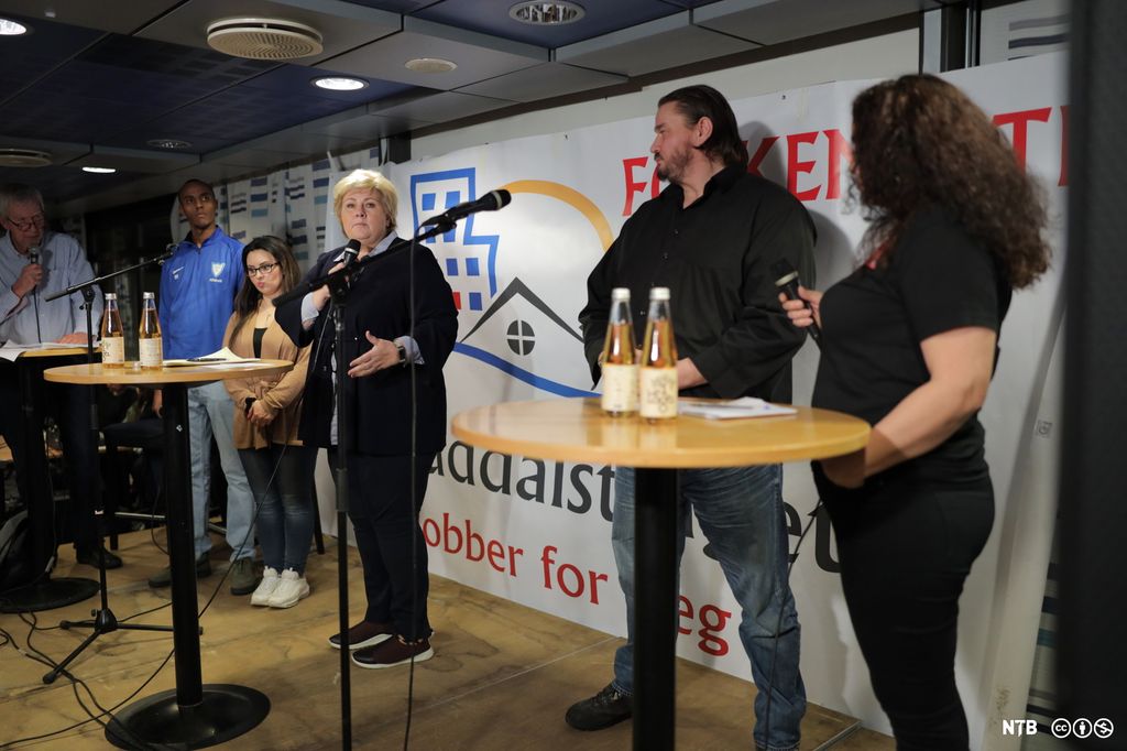Statsminister Erna Solberg snakker på et podium med fire andre deltakere på Groruddalstinget. Foto.