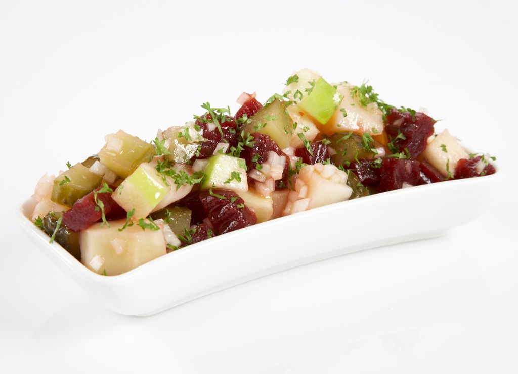 En hvit, avlang serveringsskål med rødbeter i potetsalat. Foto.