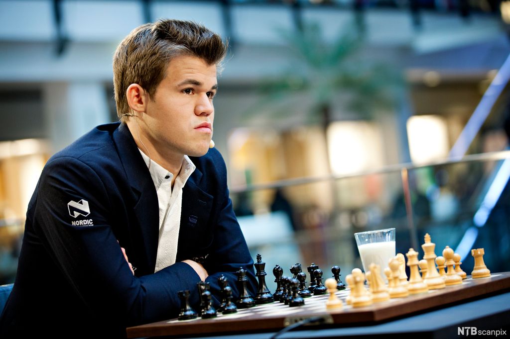 Sjakkspiller Magnus Carlsen sitter ved et sjakkbrett.