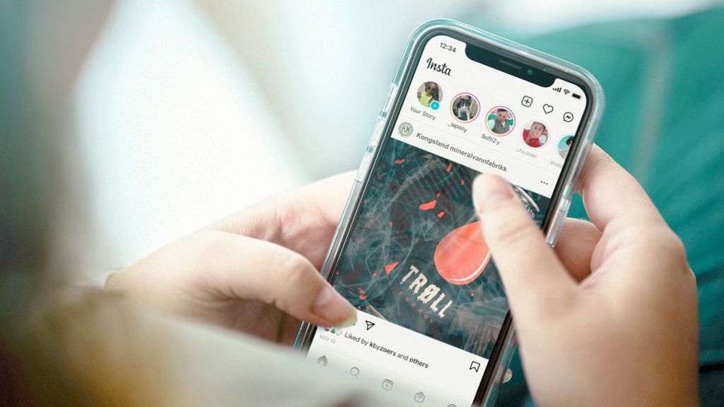 En person som holder en mobiltelefon som viser et innlegg på Instagram fra Kongsland mineralvannfabrikk om den nye drikken Trøll. Foto.