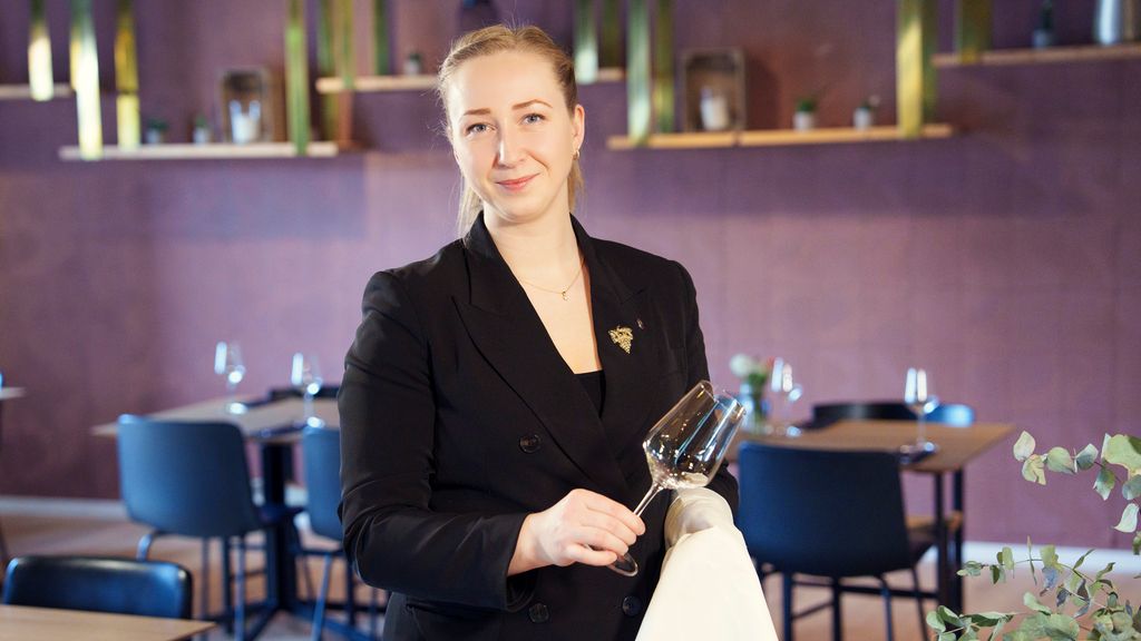 Kelner pusser et vinglass. Foto.